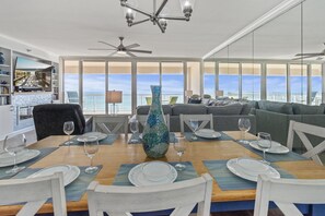 Enjoy meals with a view of the ocean from this dining area, featuring a table for four and a balcony with a railing.