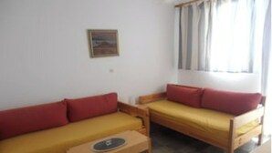 A small, compact room with two single beds, a small table, and a single wall-mounted shelf. - Eleonas apartment on the 1st floor with unobstructed ocean views (Rethymno)
