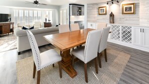 A dining area with a wooden table and chairs, a sofa, and a kitchen in the background. - Inlet View 2 BR Condo! Marlin Quay 206 (Garden City)