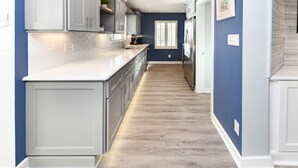 A kitchen with white cabinets, a marble countertop, and a blue wall. - Inlet View 2 BR Condo! Marlin Quay 206 (Garden City)