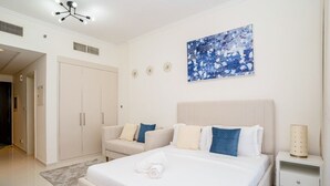 Hotellihuone, jossa on suuri sänky, sohva, vaatekaappi ja taulu seinällä.