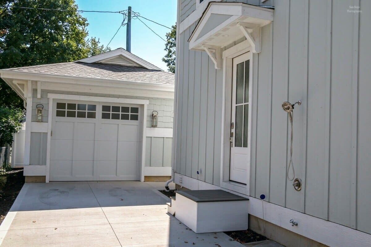 A two-car garage attached to a house with a front porch and a door with a decorative handle.