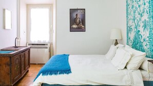 Et soveværelse med seng, skrivebord, stol, et vindue og et plakat på væggen.