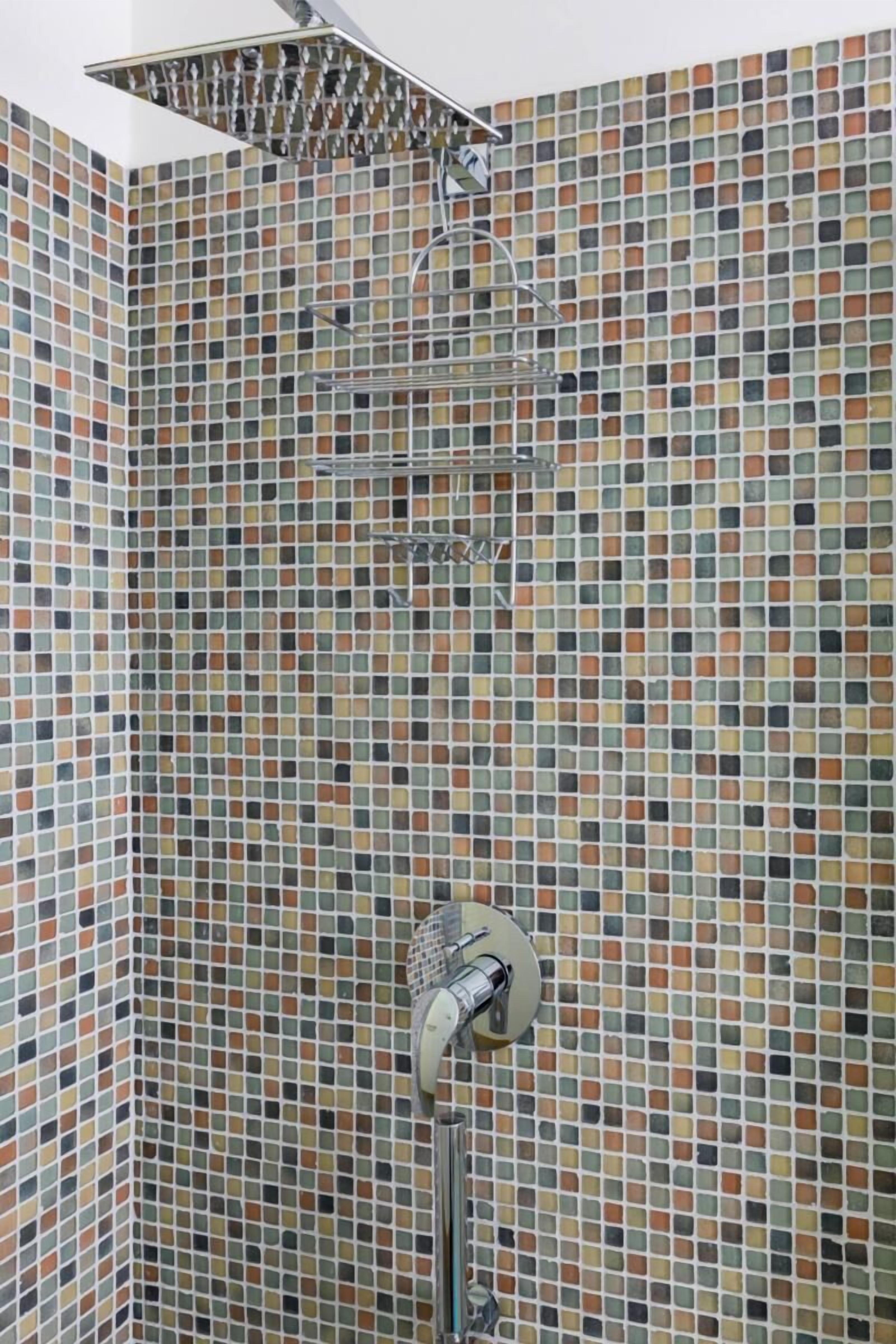 A shower area with a tiled wall and a showerhead.