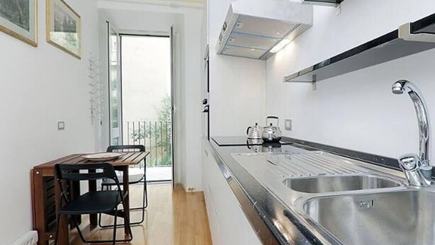 A modern kitchen with a large stainless steel sink, a built-in oven, and a dining area with a wooden table and chairs. - Palestrina   Prati area, Rome (ROMA)