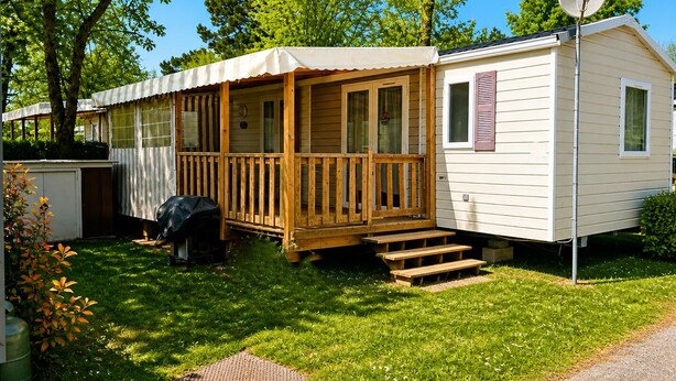 Ein Wohnmobil mit Veranda, Satellitenschüssel und Grill im Garten.