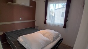Ein Einzelbett mit weißer Bettwäsche in einem Zimmer mit Fenster und Vorhängen.