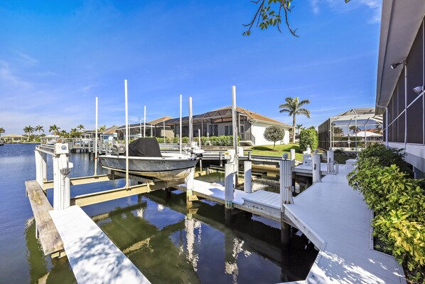 Un port de plaisance avec des bateaux amarrés, une jetée en bois et une maison dotée d’un patio couvert.