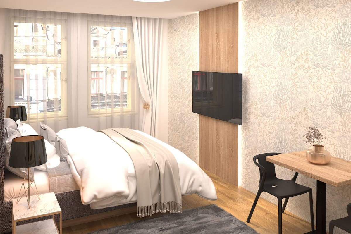 A modern hotel room with a bed, a TV mounted on the wall, a small table, and a chair.