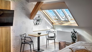 Une chambre de style loft moderne, dotée d’une fenêtre de toit, d’un bureau, de deux chaises, d’un lit et d’un radiateur.