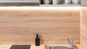 Une cuisine moderne dotée d’un évier encastré, d’un plan de travail noir et d’un pare-feu en bois.