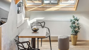 Une chambre de style loft moderne, dotée d’une lucarne, de poutres en bois, d’un coin repas et d’une plante en pot.