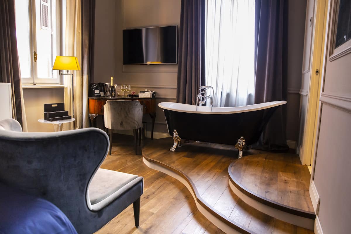 Un baño moderno con una bañera independiente, un tocador con espejo y una zona de estar con una silla y una pequeña mesa.