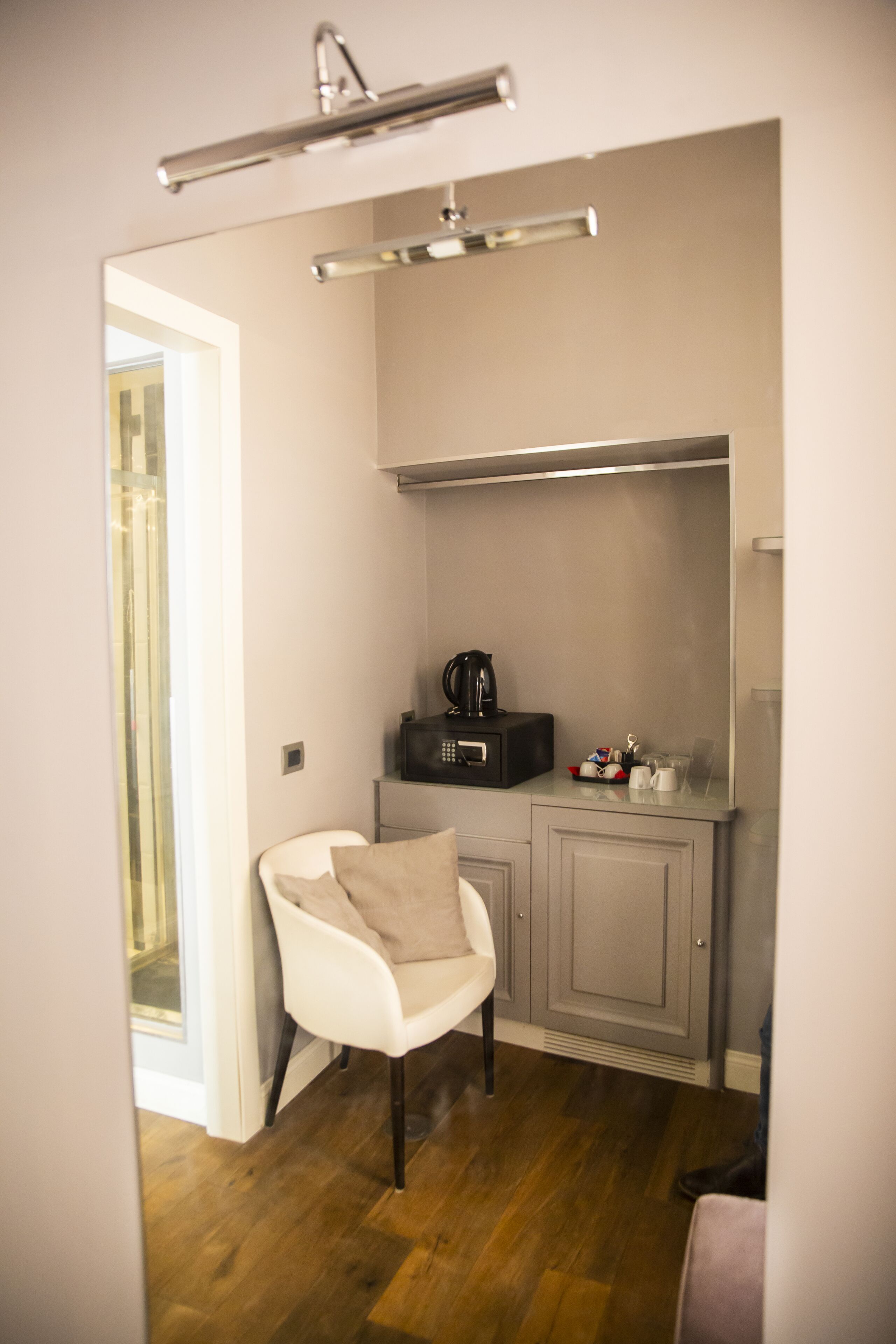 A compact kitchen with a white chair, a coffee maker, and a cabinet.