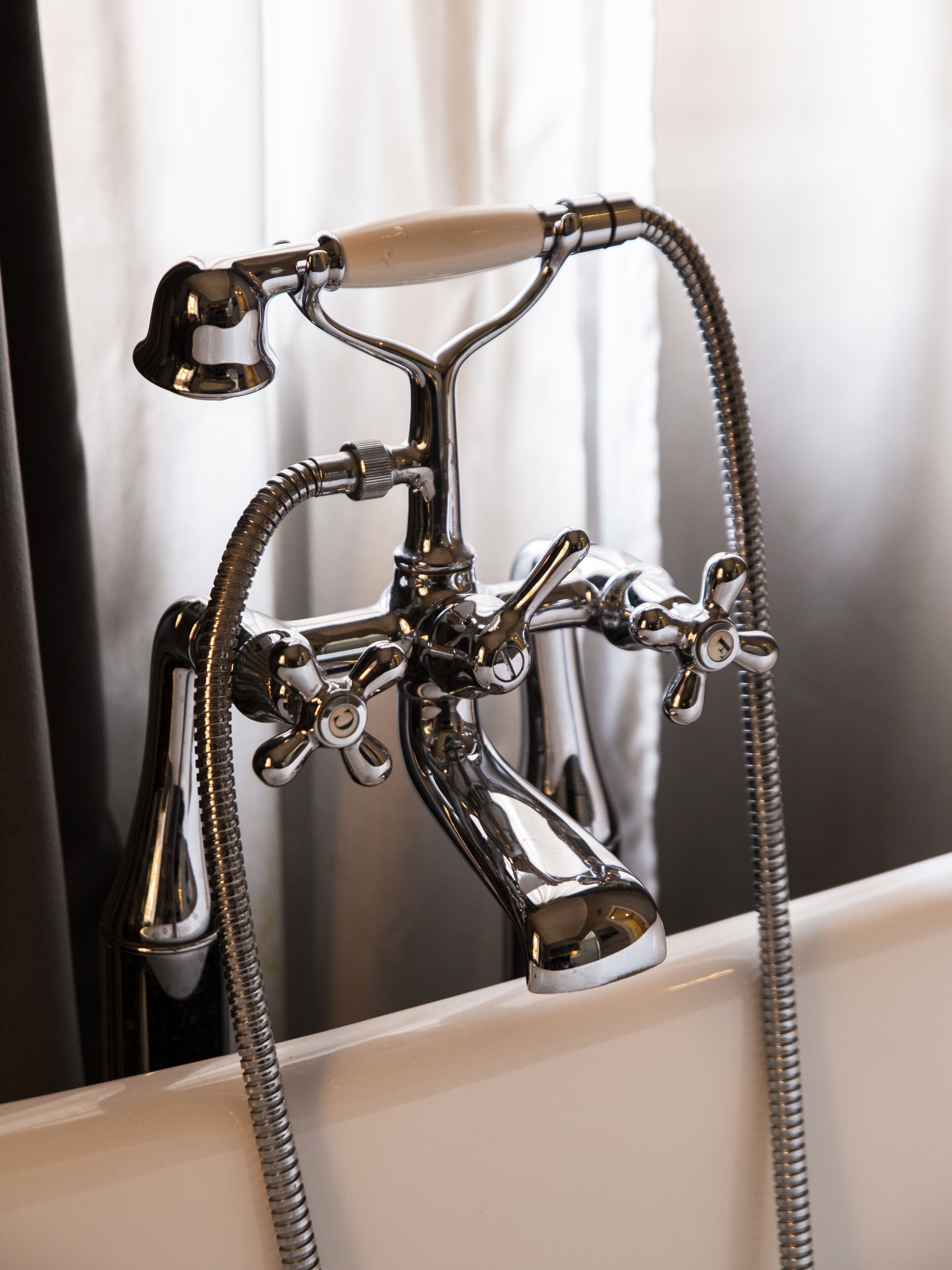 Un accesorio de baño cromado con varios controles y un manguera flexible.