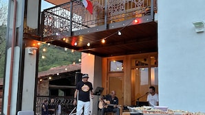 Une terrasse extérieure avec une scène, des guirlandes lumineuses et une table de buffet.