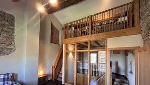 Une pièce comprenant un lit, un escalier en bois et une mezzanine avec une rambarde.