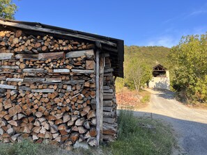 A rustic cabin with a stone wall and a wooden roof, surrounded by a gravel path and greenery. - Il Gattopardo, ART HOUSE private villa 19 quests, near Mediterranean coast. (Liguria)