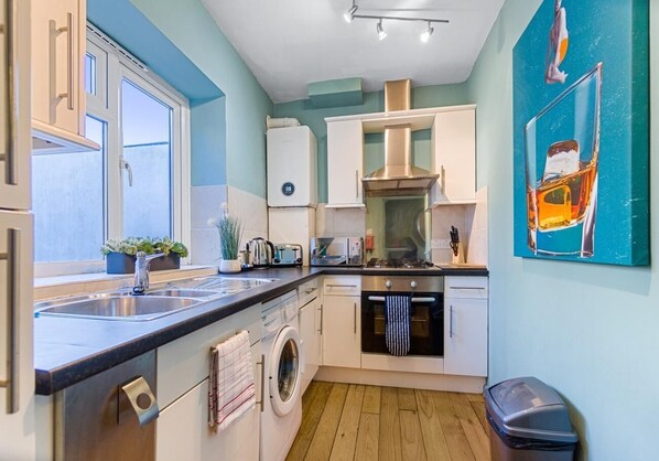 Una cocina moderna con lavadora incorporada, estufa y lavabo.