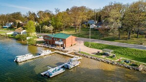 Une propriété au bord du lac, dotée d’un quai, de bateaux et d’un bâtiment surmonté d’un toit végétalisé.