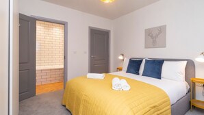 Una camera da letto moderna con un letto, una testiera, un’opera d’arte appesa al muro e una porta che dà su un balcone.