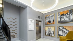 Una hall moderna con una scala, un ascensore e un cartello che indica la sua posizione.