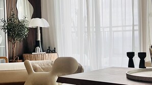 Un salon moderne avec une grande fenêtre, un canapé, une table basse et une plante décorative.