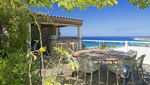 Une terrasse extérieure avec une table ronde et des chaises, offrant une vue sur la côte.