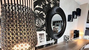 Un espace repas moderne avec une table en bois, un mur orné d’un motif noir et blanc, et une lampe noire décorative.