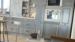 Une cuisine moderne avec des meubles gris, un four à micro-ondes et un four traditionnel. On y trouve également un coin repas avec une table et des chaises.