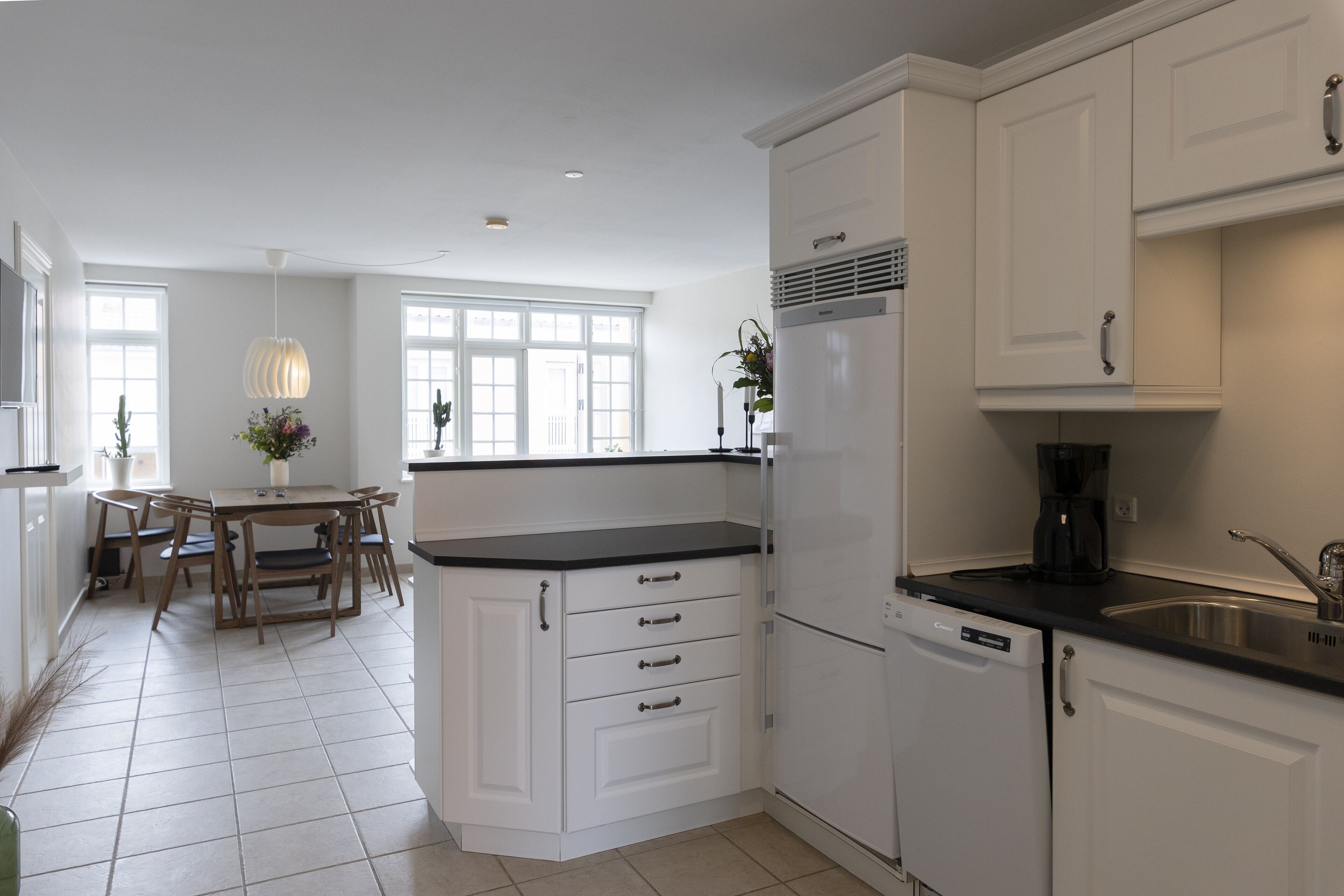 A modern kitchen with white cabinets, a black countertop, and a built-in dishwasher.