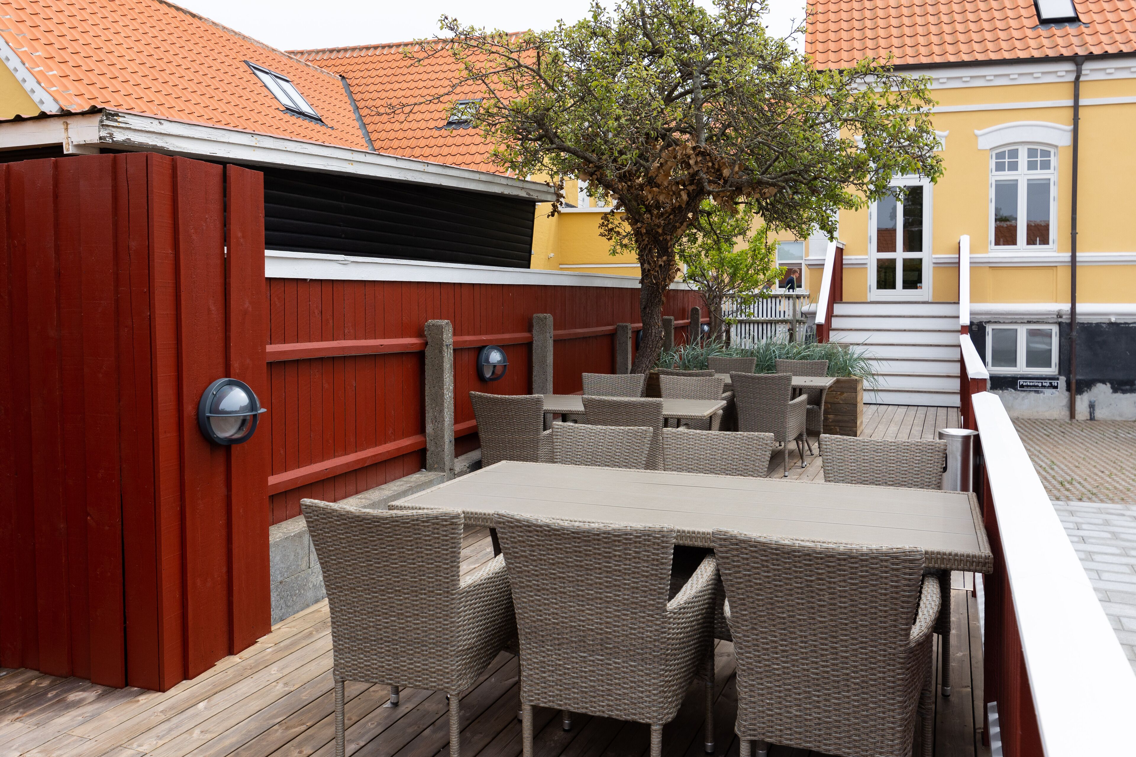A patio area with wicker furniture and a red fence.