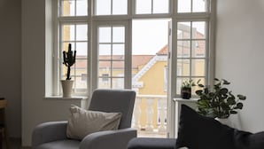 Un salon avec un fauteuil gris, un canapé noir et une plante en pot.