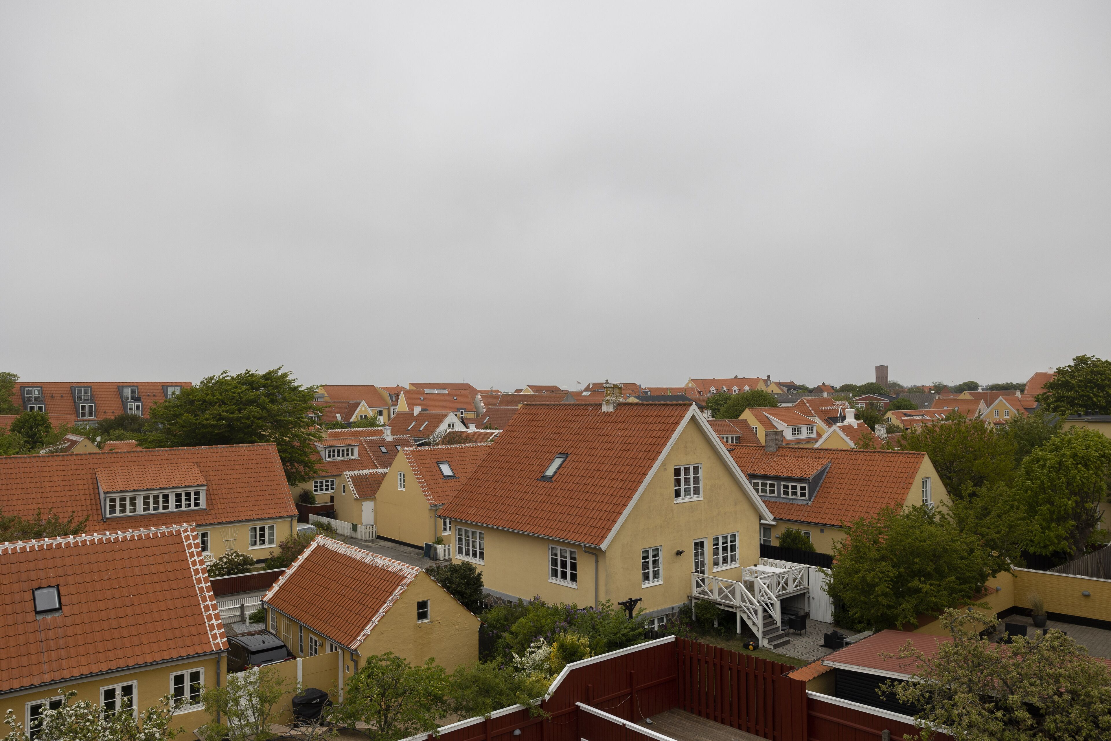 A residential area with houses featuring red-tiled roofs and yellow facades.