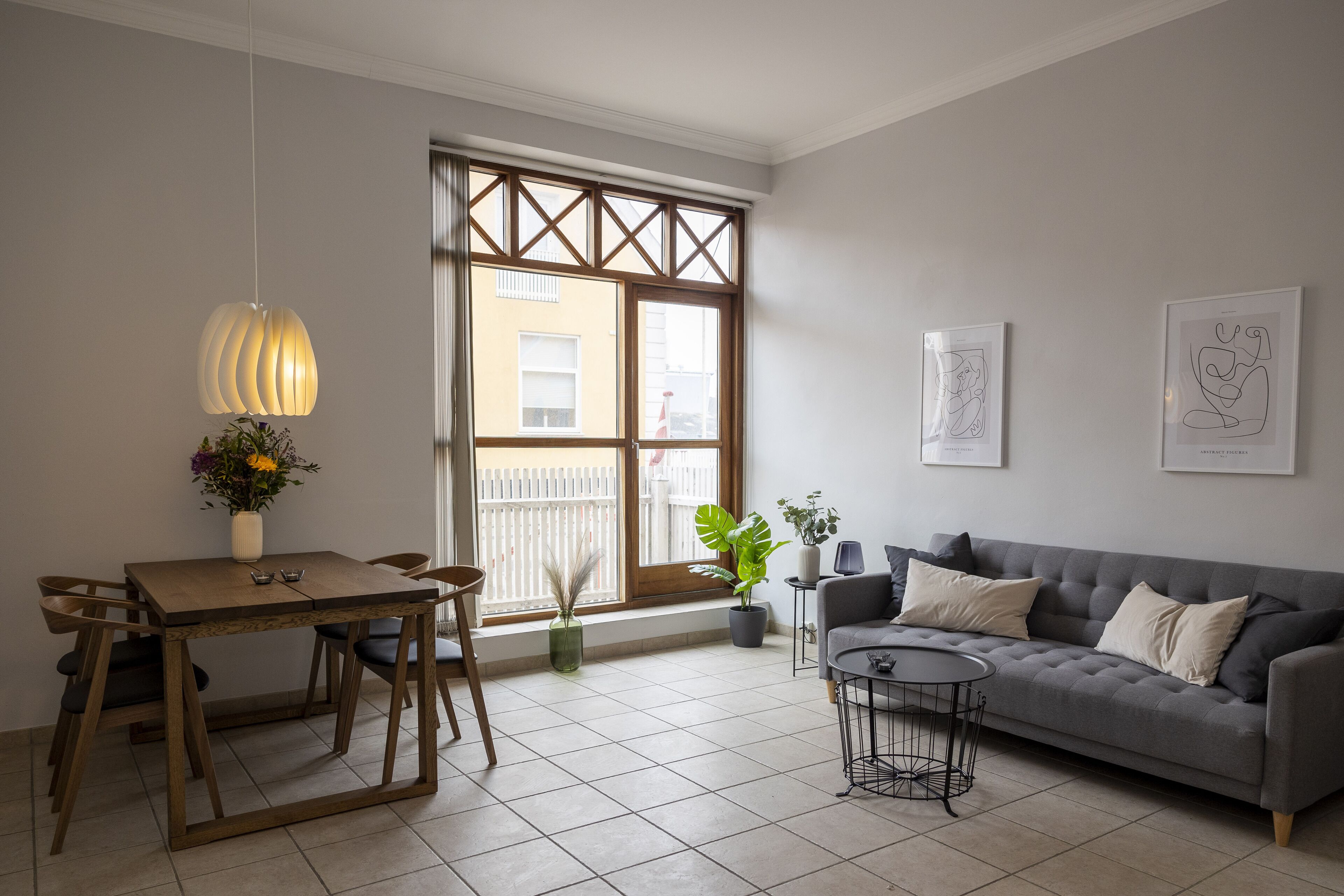 A modern living room with a dining table, sofa, and large window.