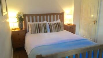 A neatly made bed with striped pillows, a wooden headboard, and two bedside tables with lamps.