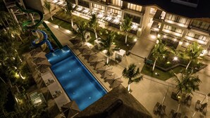 Un hôtel doté d’une piscine, de plusieurs balcons et de palmiers.