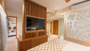 Un dormitorio moderno con un televisor grande, paneles de madera y una colcha estampada.