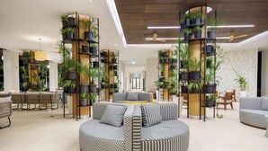 Un hall d’entrée spacieux avec un espace salon central, de nombreuses installations végétales verticales et un ventilateur de plafond moderne.