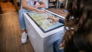 A person interacting with a digital table displaying a sports game.