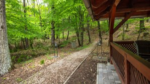 A covered wooden deck with a gravel path leading into a forest.