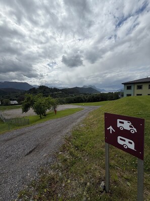 Un chemin de gravier mène à un bâtiment sur lequel est apposée une pancarte indiquant un espace de stationnement pour les véhicules.