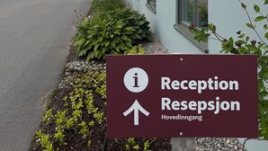 A building with a reception sign, a paved entrance, and a row of windows.