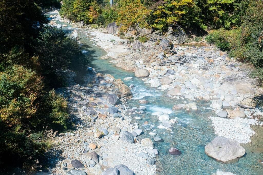 A river with clear water surrounded by rocks and trees.