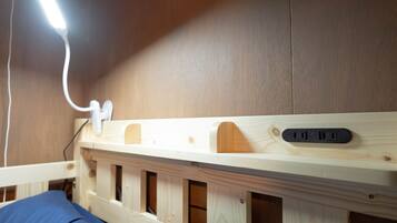 A wooden bunk bed with a headboard that includes a power outlet and USB ports.