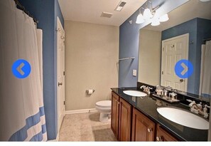 A bathroom with two sinks, a toilet, and a shower.