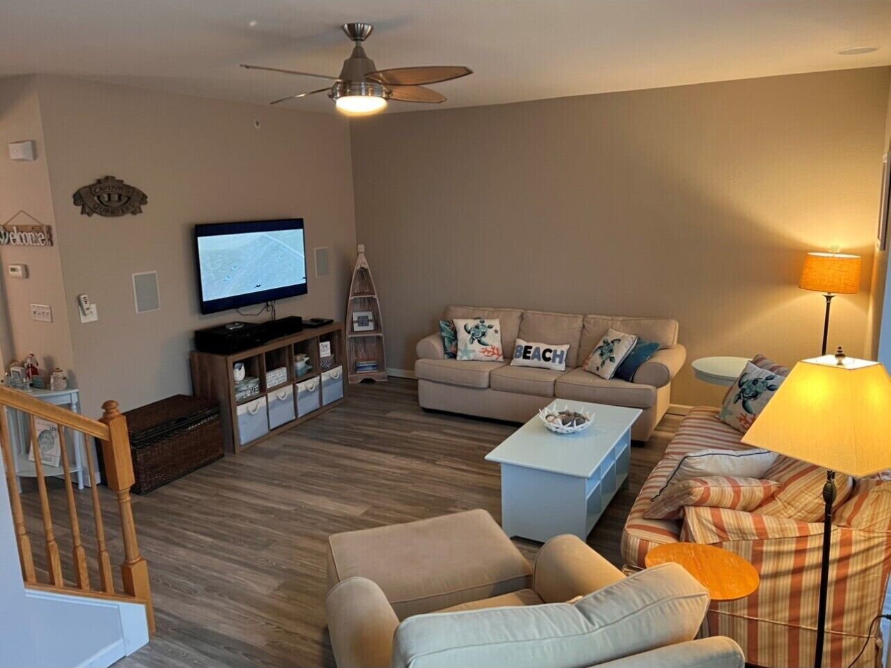 A living room with a television, two sofas, a coffee table, a lamp, and a staircase.