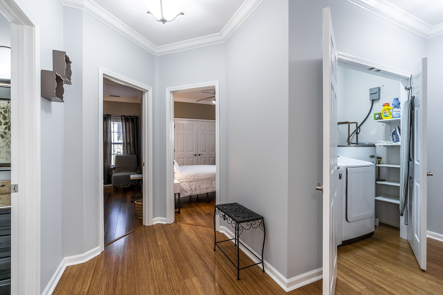 Un couloir avec une petite table, un lit et un réfrigérateur dans un espace de vie compact.