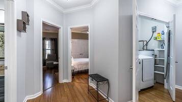 Un couloir avec une petite table, un lit et un réfrigérateur dans un espace de vie compact.