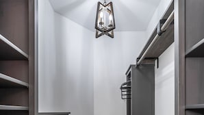 A narrow walk-in closet with wooden flooring, grey shelving units, and a hanging light fixture. - Entire Home in Hamburg! (Lexington)